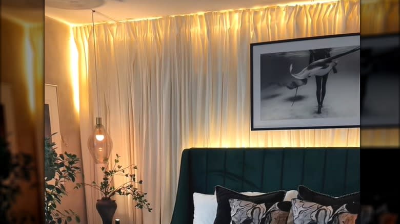 Bright light behind thin white curtains on stylish bedroom wall